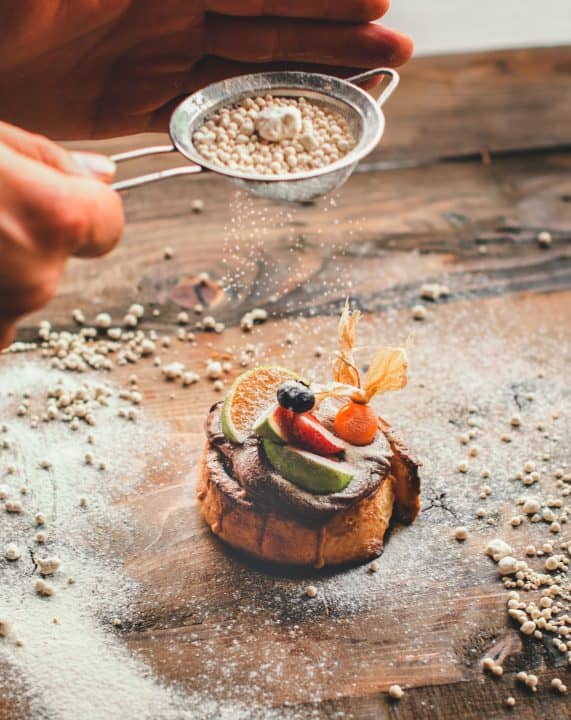 a person is sprinkling sugar on a dessert